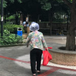 中国で、突然の雨にビニール袋をかぶるおばさん