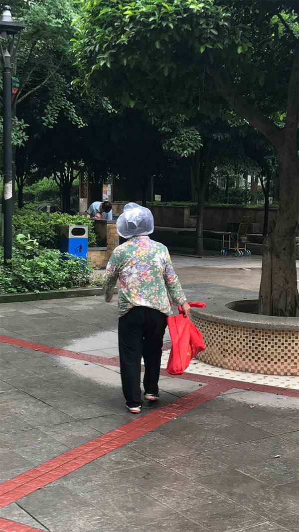 中国で、突然の雨にビニール袋をかぶるおばさん