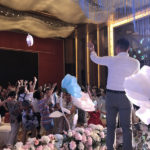 歌を歌いながらぬいぐるみをゲストに投げる中国の結婚式の司会者