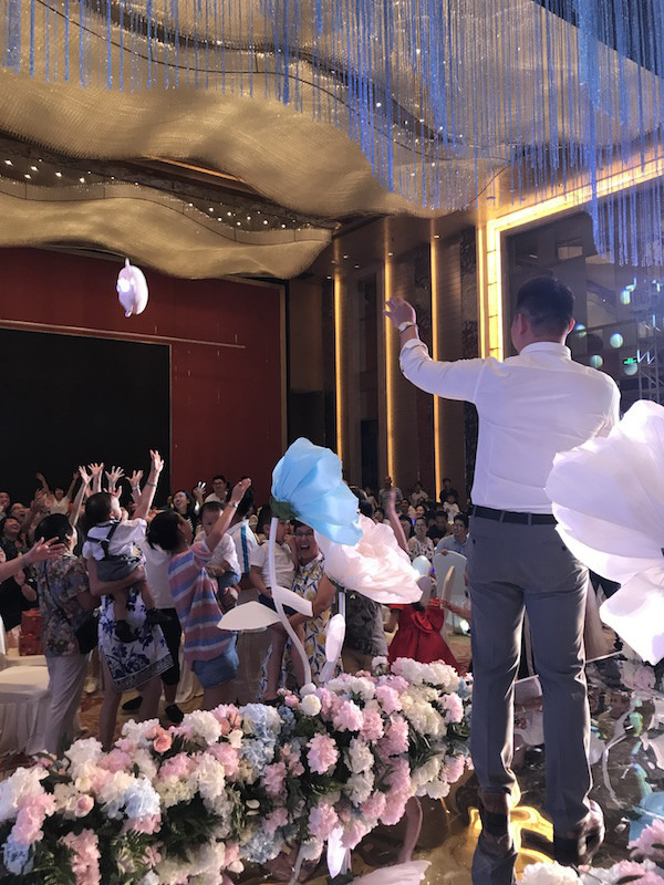 歌を歌いながらぬいぐるみをゲストに投げる中国の結婚式の司会者
